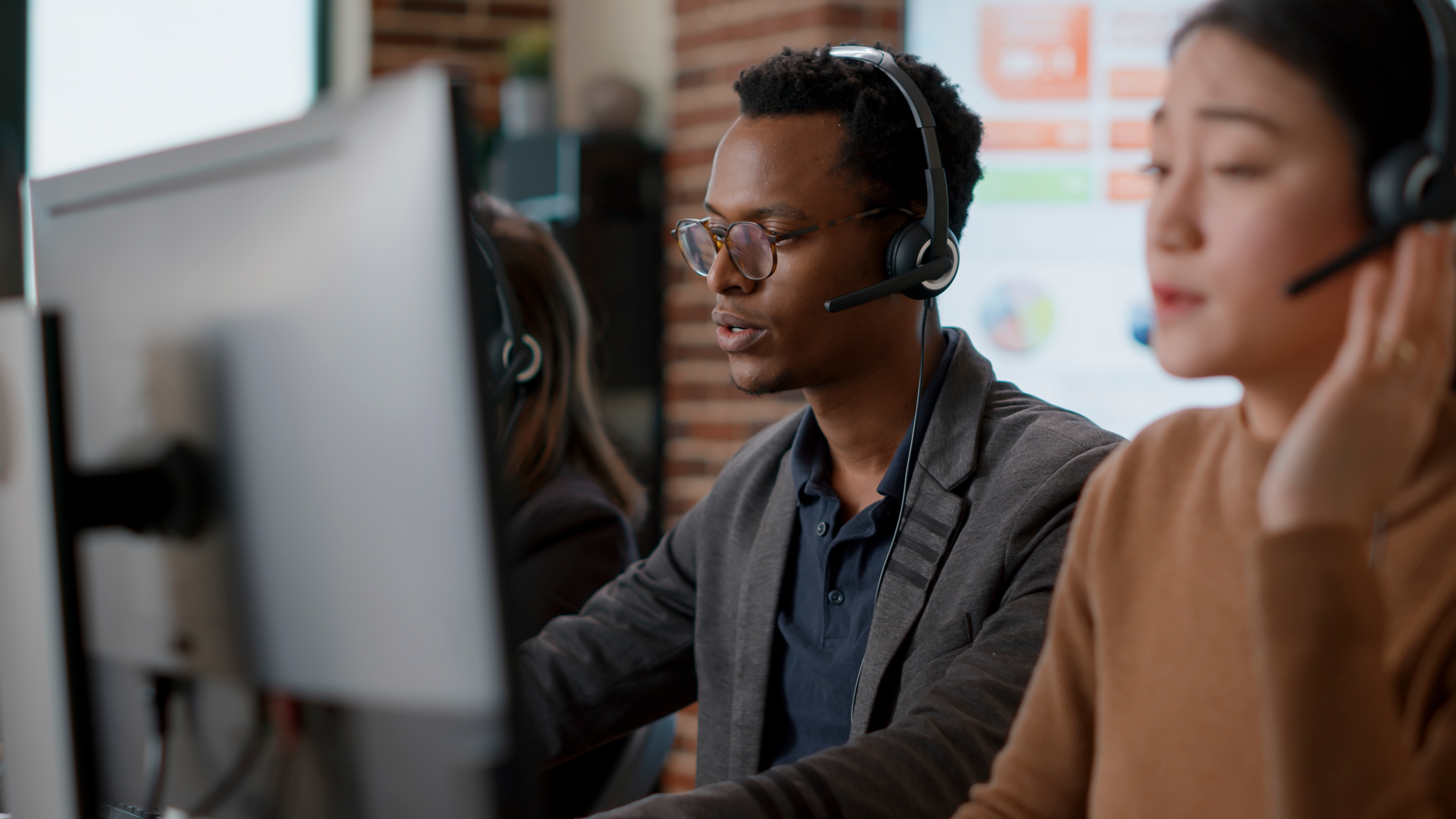 A male customer service representative using headset helps callers.