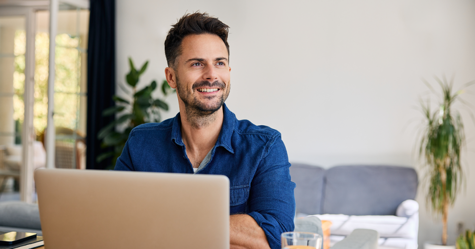 A man sits at a table with an open laptop.